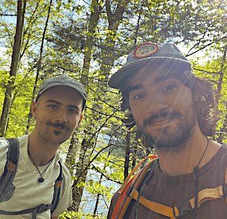 Here's an alt tag for the image: Two men hiking in a forest.