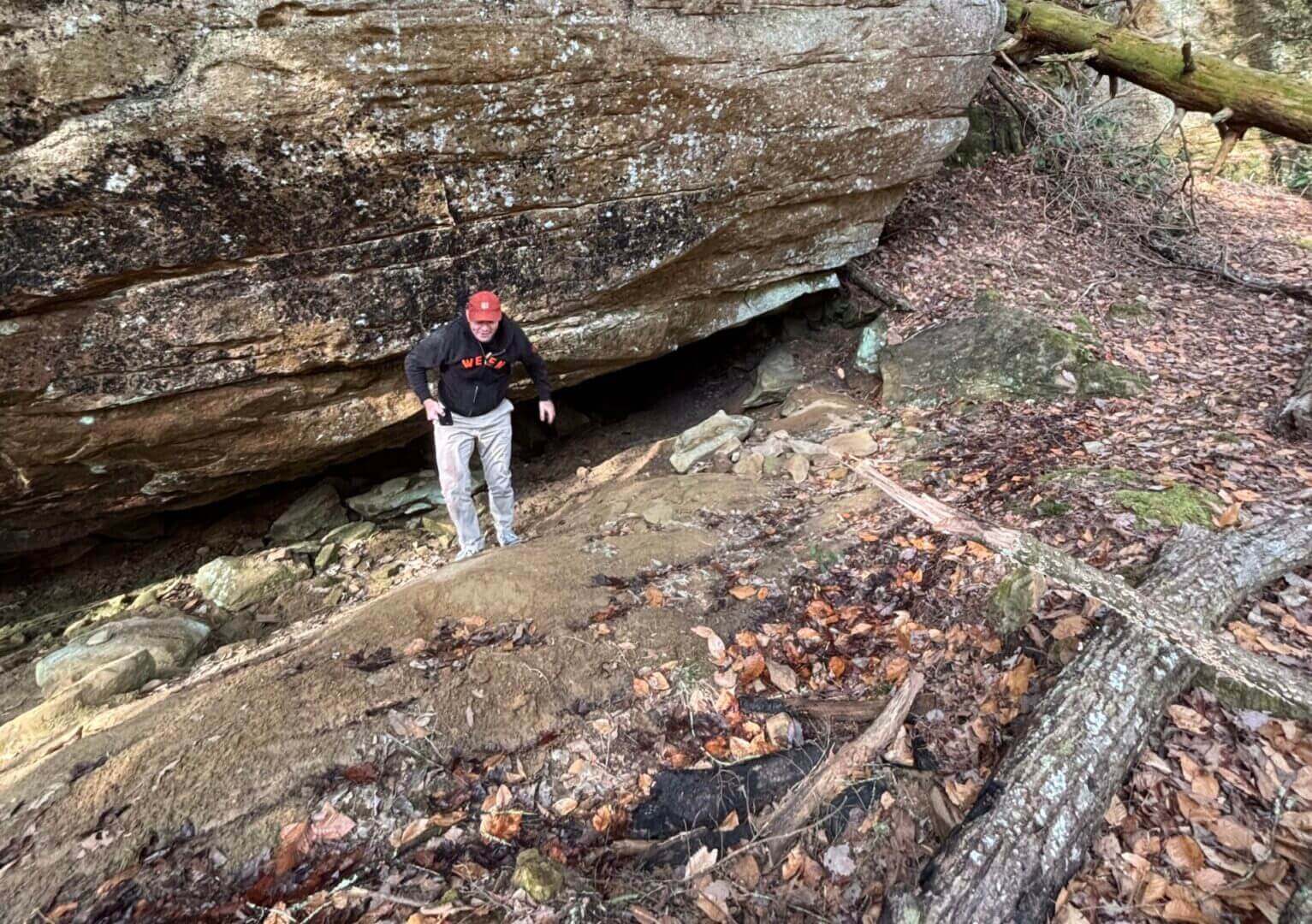 Person hiking near large rock formation outdoors.